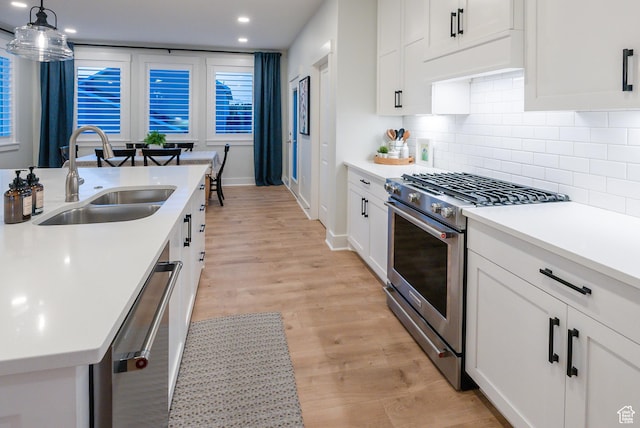 kitchen with appliances with stainless steel finishes, a sink, decorative backsplash, light countertops, and white cabinets