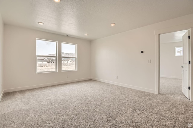 unfurnished room featuring light carpet, baseboards, a textured ceiling, and recessed lighting