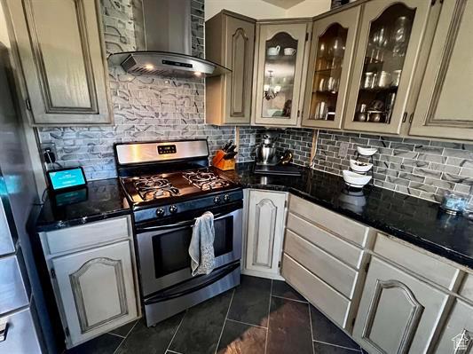 1204 Nashua Cir, Soda Springs, ID 83276 - kitchen with stainless steel appliances, wall chimney exhaust hood, decorative backsplash, and dark tile patterned floors