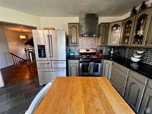 1204 Nashua Cir, Soda Springs, ID 83276 - kitchen with appliances with stainless steel finishes, wall chimney range hood, decorative backsplash, glass insert cabinets, and a textured ceiling