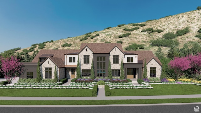view of front facade with stone siding, a mountain view, and a front yard