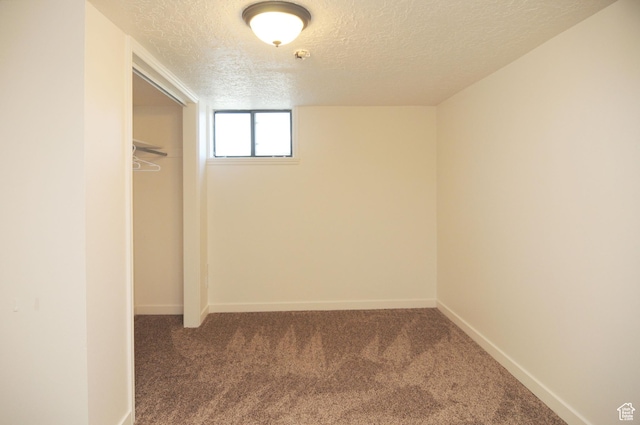 basement with a textured ceiling, carpet floors, and baseboards