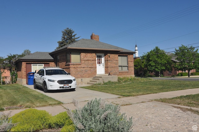 bungalow-style house featuring brick siding, driveway, a front lawn, and a chimney