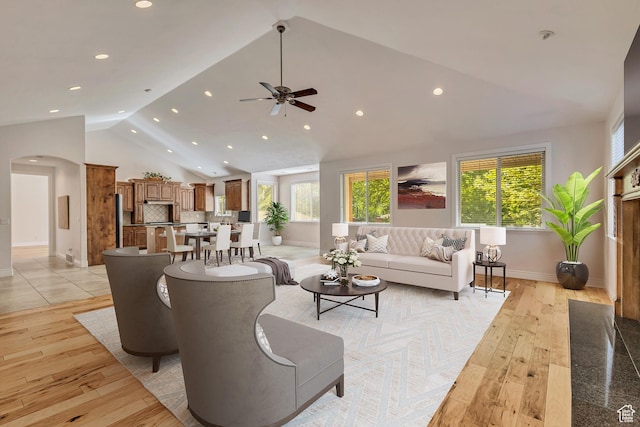 living room with lofted ceiling, healthy amount of natural light, recessed lighting, light wood-type flooring, and arched walkways