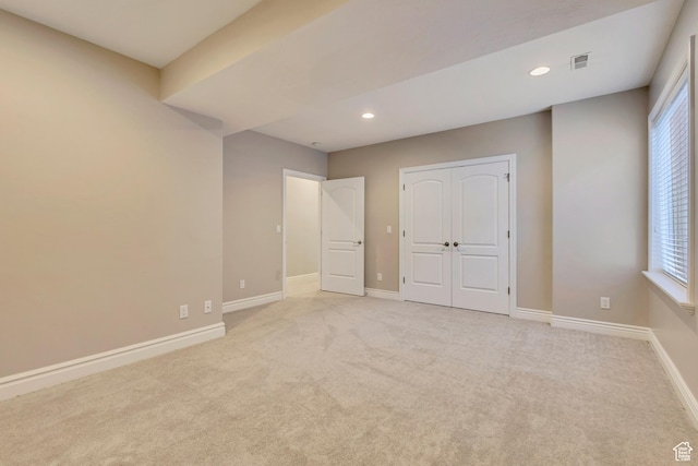 unfurnished bedroom with baseboards, recessed lighting, light colored carpet, and a closet