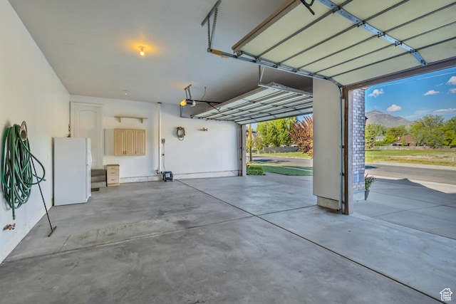 garage featuring freestanding refrigerator, a garage door opener, and a mountain view