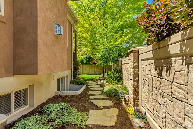 view of side of home with stucco siding and fence