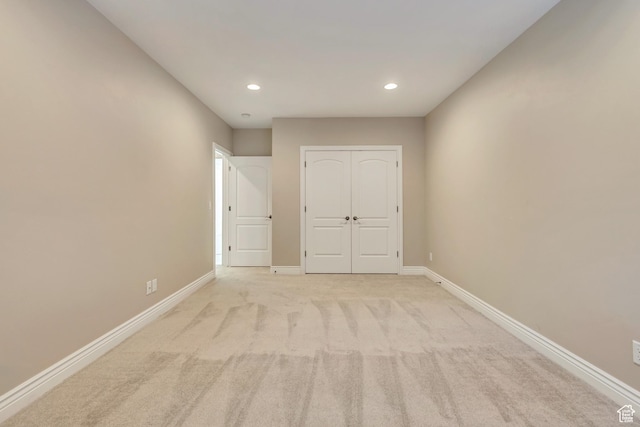 unfurnished bedroom featuring recessed lighting, baseboards, a closet, and light carpet