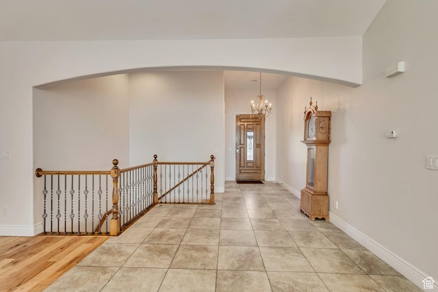 foyer entrance with arched walkways, a chandelier, baseboards, and light tile patterned floors