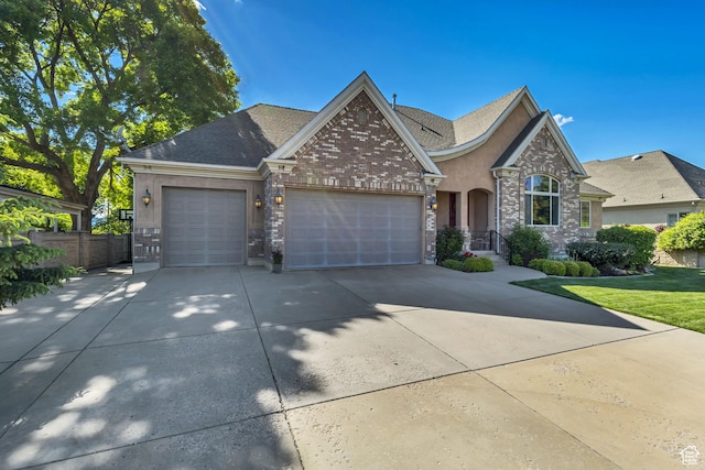 view of front of property with an attached garage, concrete driveway, fence, stucco siding, and brick siding