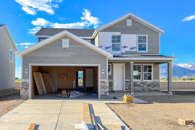 view of front of property with driveway, stone siding, a garage, and covered porch