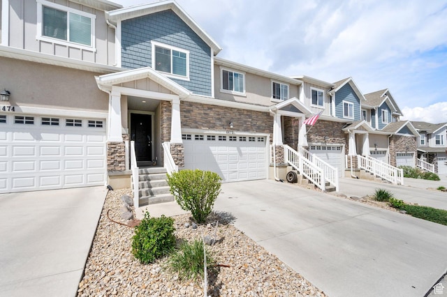 view of front facade with a garage, concrete driveway, stone siding, and a residential view