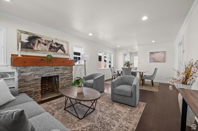living room featuring ornamental molding, recessed lighting, wood finished floors, baseboards, and a stone fireplace