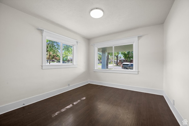 unfurnished room featuring dark wood-style floors and baseboards