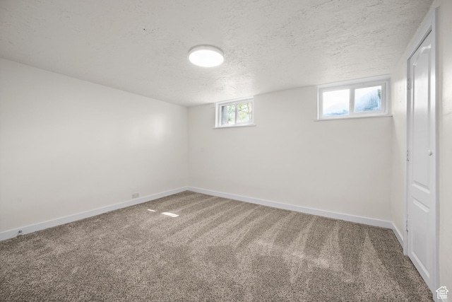 below grade area with carpet, baseboards, and a textured ceiling