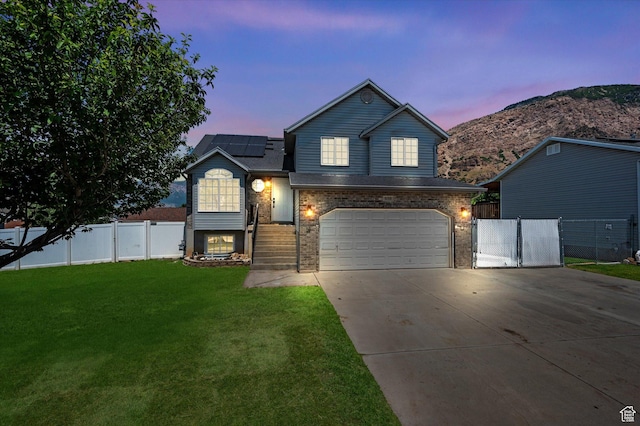 850 E Village Rd N, Ogden, UT 84404 - view of front of property featuring driveway, roof mounted solar panels, an attached garage, brick siding, and a mountain view