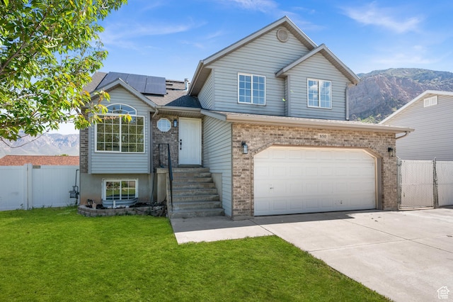 850 E Village Rd N, Ogden, UT 84404 - view of front of home featuring concrete driveway, solar panels, an attached garage, and a mountain view