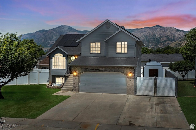 850 E Village Rd N, Ogden, UT 84404 - traditional-style home featuring roof mounted solar panels, a mountain view, an attached garage, driveway, and a gate