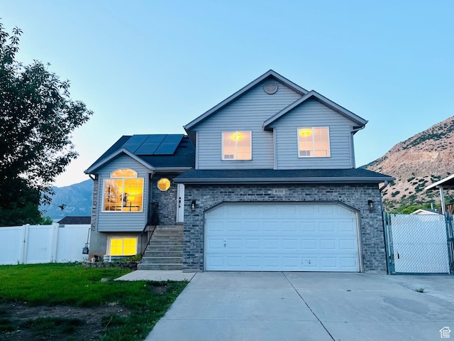 850 E Village Rd N, Ogden, UT 84404 - traditional-style house with a gate, roof mounted solar panels, an attached garage, and a mountain view