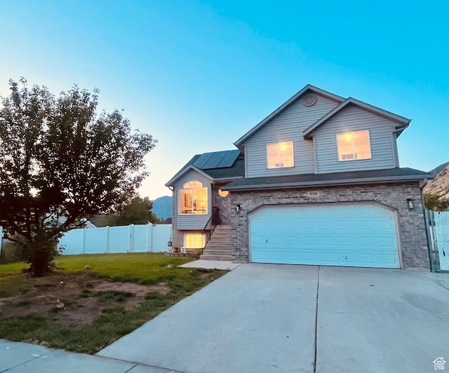 850 E Village Rd N, Ogden, UT 84404 - traditional home featuring solar panels, a garage, concrete driveway, and stone siding