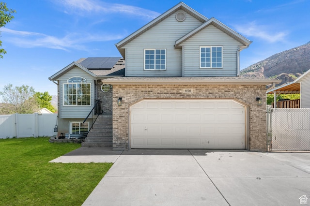 850 E Village Rd N, Ogden, UT 84404 - view of front of home with a gate, roof mounted solar panels, driveway, brick siding, and a garage