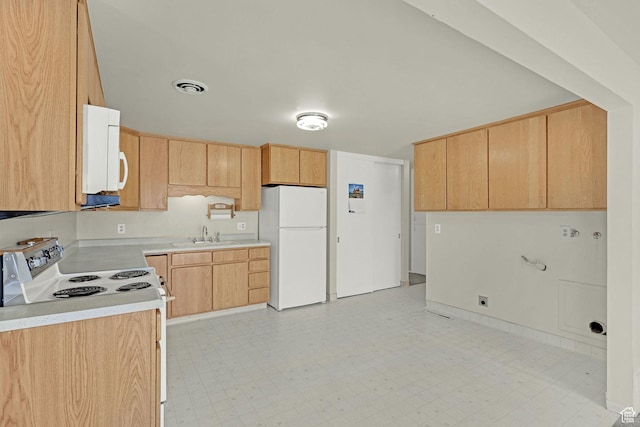 kitchen featuring white appliances, light countertops, light brown cabinetry, a sink, and light floors