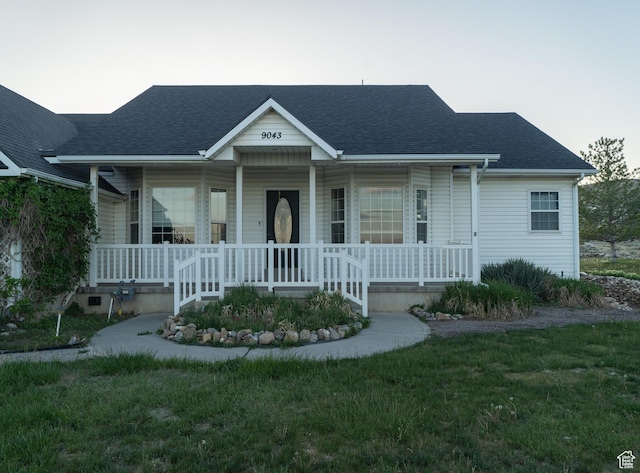 view of front of property featuring a porch, a shingled roof, and a front lawn