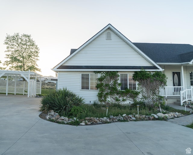 view of property exterior with driveway, a carport, covered porch, and a shingled roof