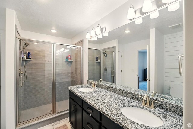 bathroom with a stall shower, recessed lighting, and double vanity