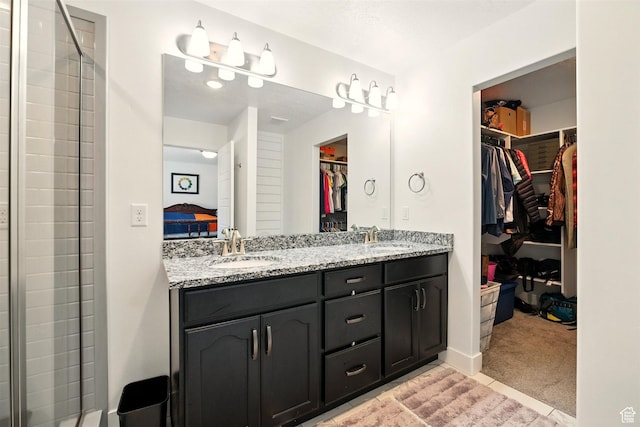 full bath with double vanity, a tile shower, connected bathroom, and a walk in closet