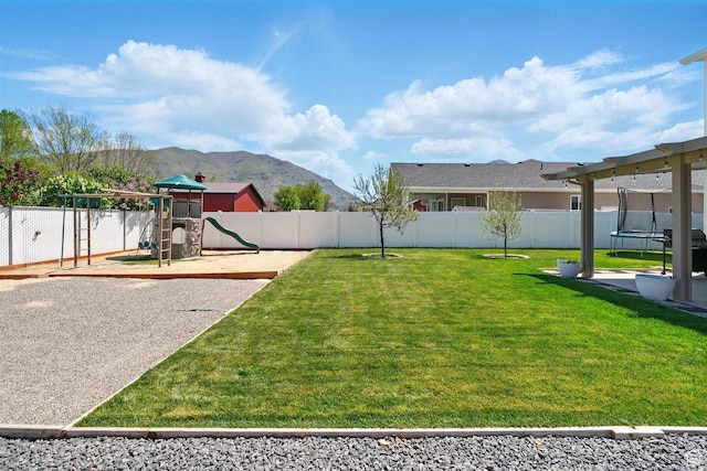 view of yard with a playground, a trampoline, and a mountain view