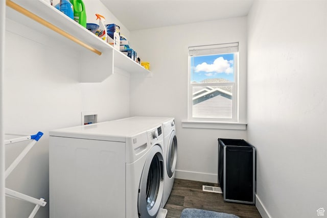 clothes washing area featuring washer and dryer, dark wood-type flooring, and baseboards