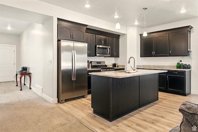 kitchen featuring stainless steel appliances, a sink, baseboards, light stone counters, and recessed lighting
