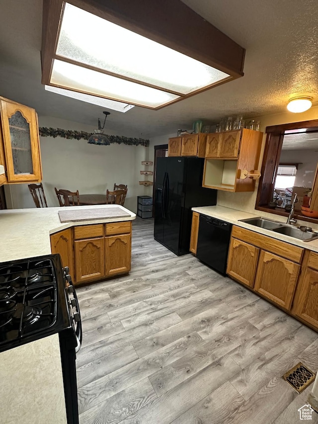 kitchen with black appliances, a sink, brown cabinets, and light countertops