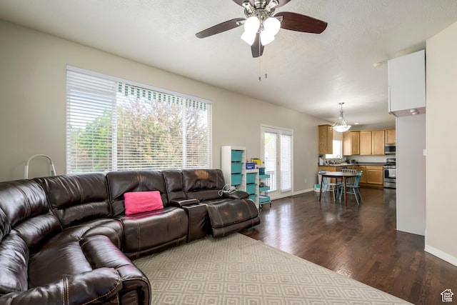 living room featuring dark wood-style flooring, a ceiling fan, baseboards, and a textured ceiling
