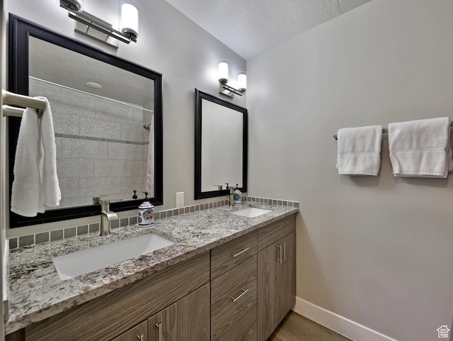 310 N N Hwy Unit 22A, Brian Head, UT 84719 - full bathroom featuring baseboards, double vanity, a textured ceiling, tiled shower, and wood finished floors