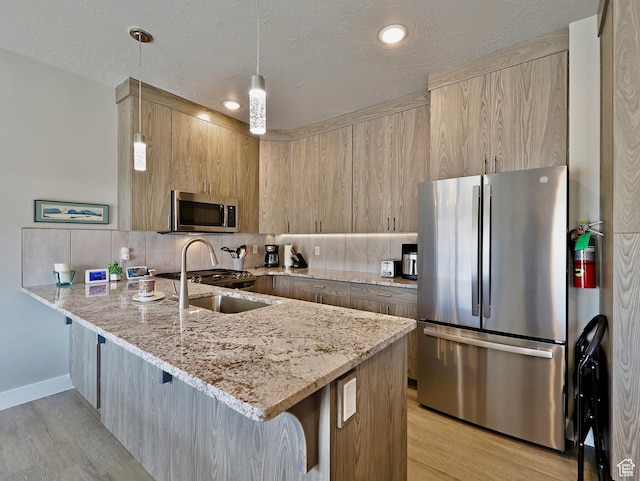 310 N N Hwy Unit 22A, Brian Head, UT 84719 - kitchen with stainless steel appliances, a peninsula, a breakfast bar, light wood finished floors, and backsplash