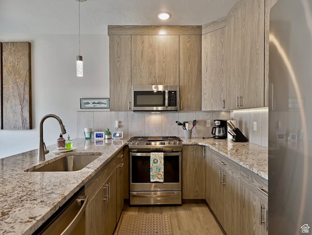 310 N N Hwy Unit 22A, Brian Head, UT 84719 - kitchen featuring stainless steel appliances, a sink, decorative backsplash, light stone counters, and light wood finished floors