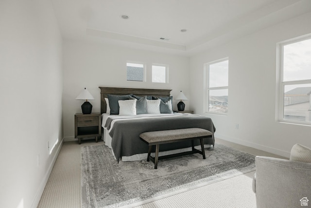 bedroom with a tray ceiling and baseboards