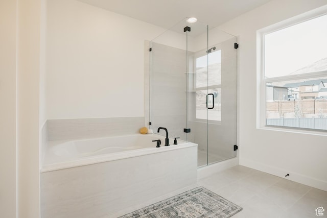 bathroom featuring a stall shower, a garden tub, tile patterned flooring, and baseboards