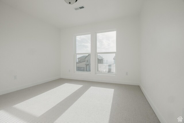unfurnished room featuring light carpet and baseboards