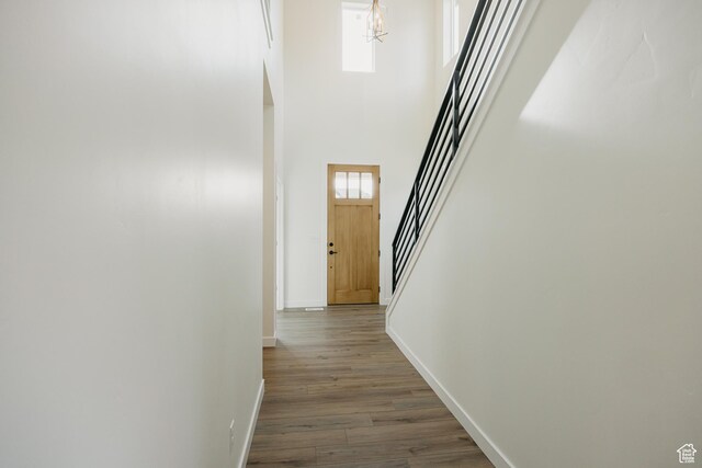 corridor with baseboards, stairs, a towering ceiling, dark wood-style flooring, and a chandelier