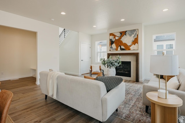 living room with wood finished floors, recessed lighting, baseboards, a tiled fireplace, and stairway