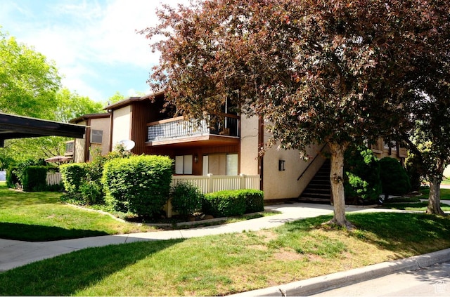 view of front facade featuring a front lawn, a balcony, and stairway
