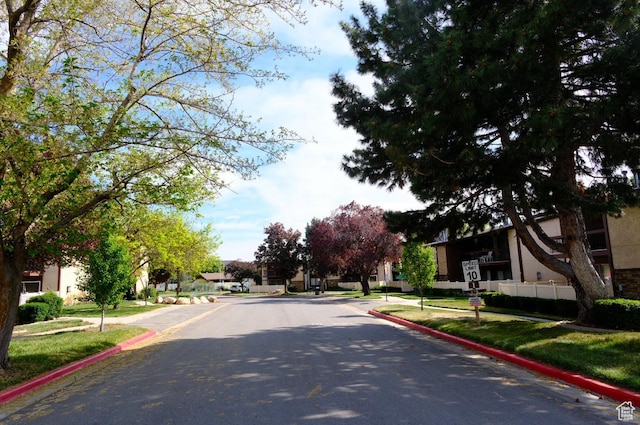 view of asphalt road featuring curbs and sidewalks