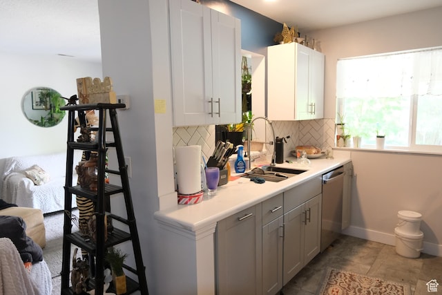 kitchen featuring a sink, stainless steel dishwasher, decorative backsplash, and light countertops