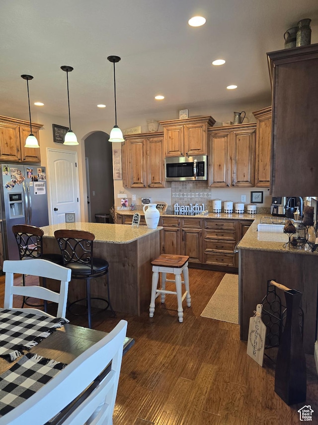 1256 Jefferson Cir, Price, UT 84501 - kitchen with appliances with stainless steel finishes, arched walkways, dark wood-type flooring, a breakfast bar area, and light stone counters