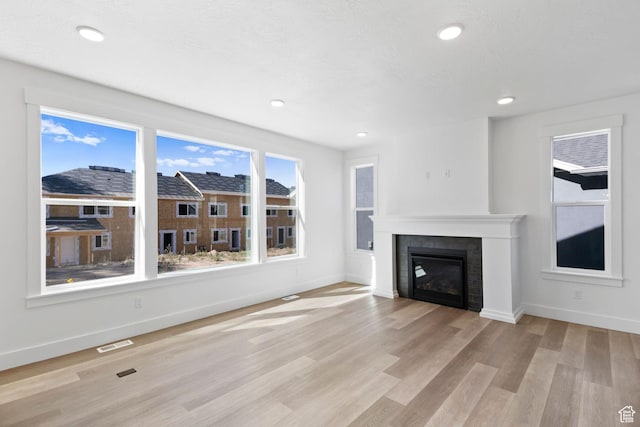 705 N Brooke Ave, Tooele, UT 84074 - unfurnished living room featuring baseboards, light wood finished floors, recessed lighting, and a tile fireplace