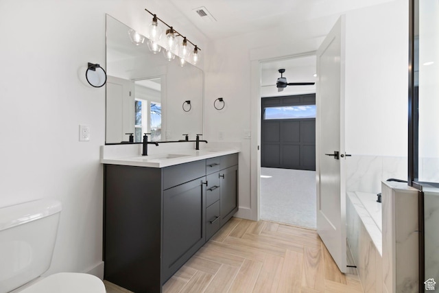 705 N Brooke Ave, Tooele, UT 84074 - bathroom featuring toilet, double vanity, a ceiling fan, and a tub to relax in