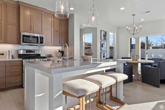 kitchen featuring stainless steel appliances, recessed lighting, tasteful backsplash, light wood-style flooring, and plenty of natural light